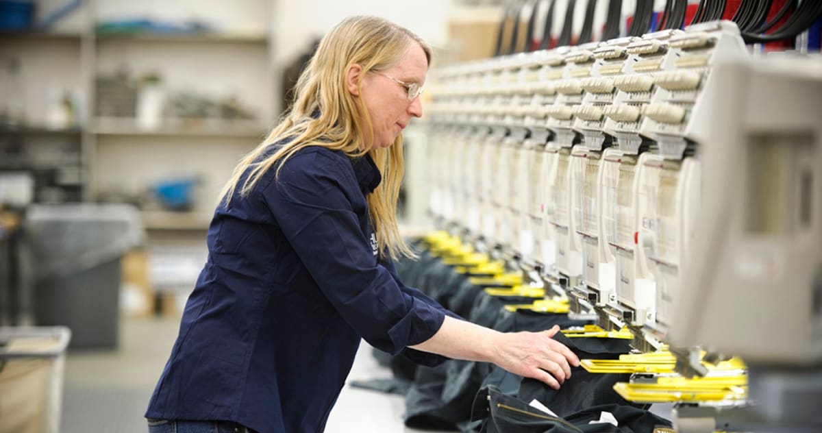 A Human Technologies employee operating an industrial embroidery machine in our Utica manufacturing facility.